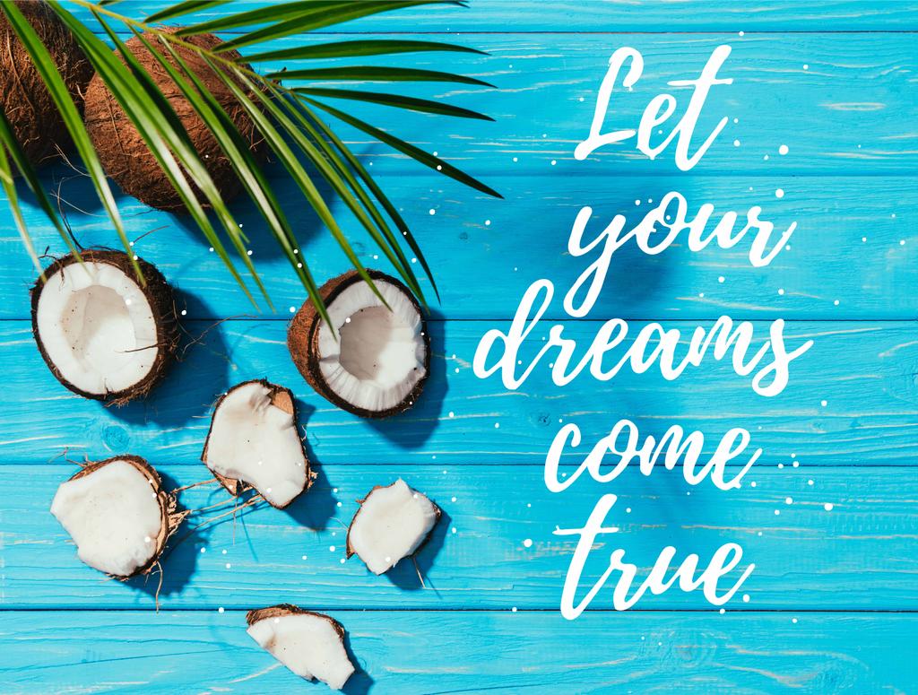 Ansicht von Kokosnüssen und grünen Palmblättern auf türkisfarbener Holzoberfläche mit dem Schriftzug "Lassen Sie Ihre Träume wahr werden"  - Foto, Bild