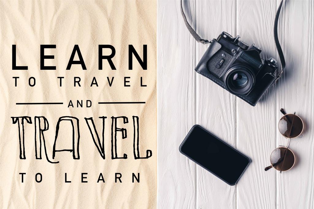 Smartphone με κάμερα και γυαλιά ηλίου στην προβλήτα στην ελαφριά άμμο με «μάθετε να ταξιδεύουν και να ταξιδέψετε για να μάθετε» γράμματα - Φωτογραφία, εικόνα