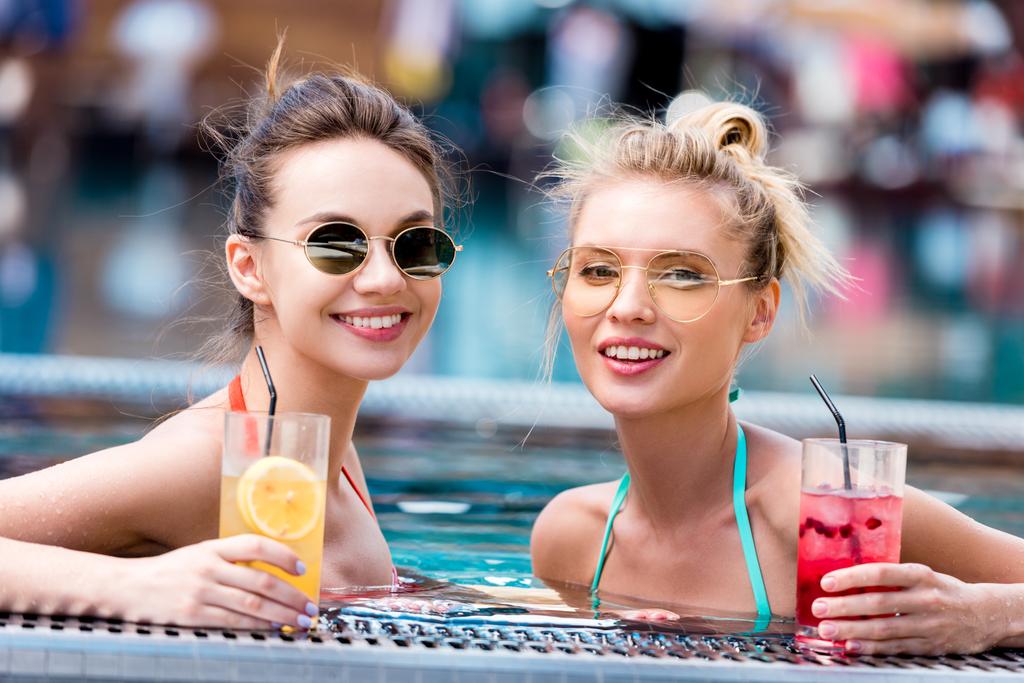 happy young women with delicious cocktails relaxing in swimming pool - Photo, Image
