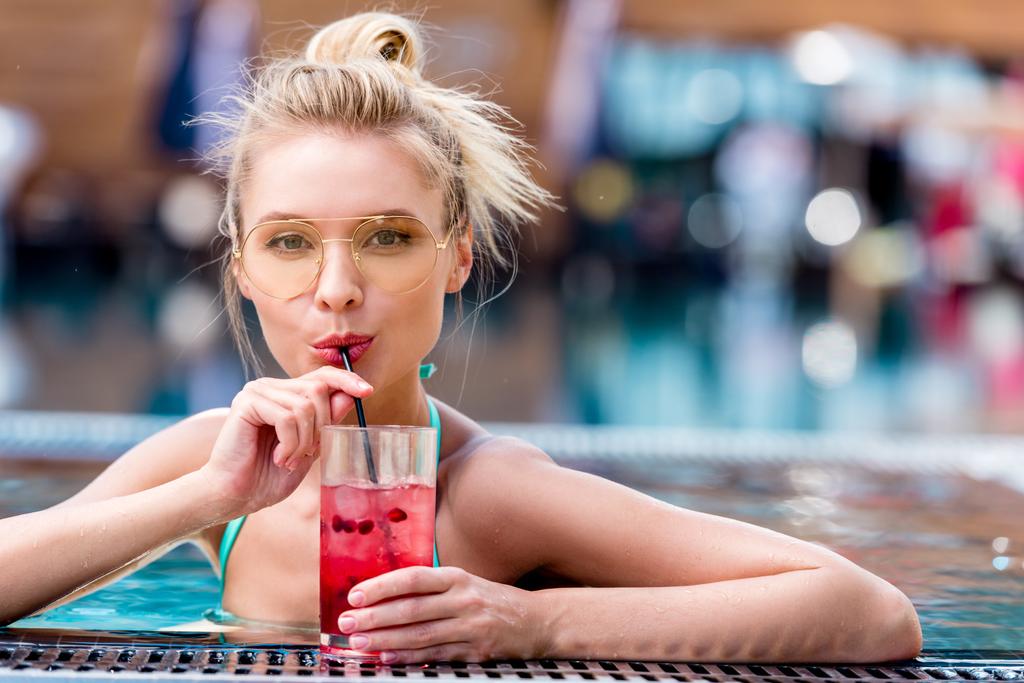 mooie jonge vrouw verse cocktail drinken bij zwembad - Foto, afbeelding