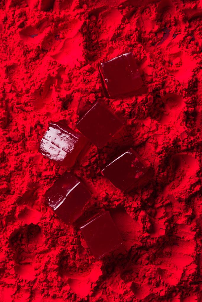 вид сверху на разбросанные конфеты на красном порошке
 - Фото, изображение