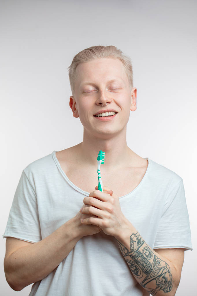 Человек с закрытыми глазами держит зубную щетку в руке. Здоровье зубов и зубов
 - Фото, изображение