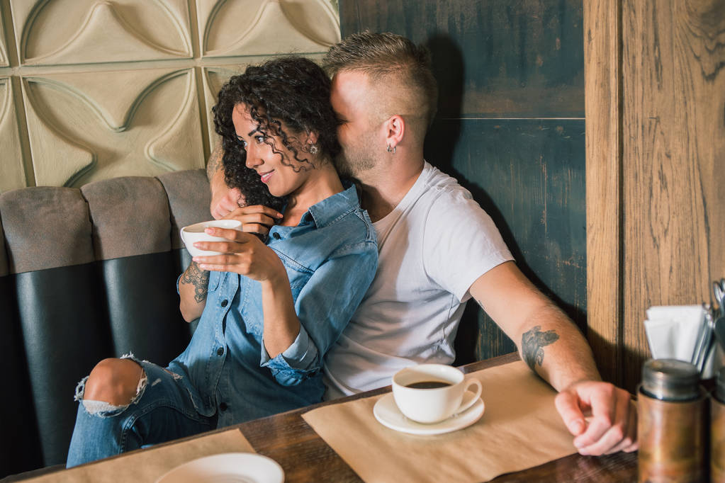 Heureux jeune couple boit du café et sourit tout en étant assis au café
 - Photo, image