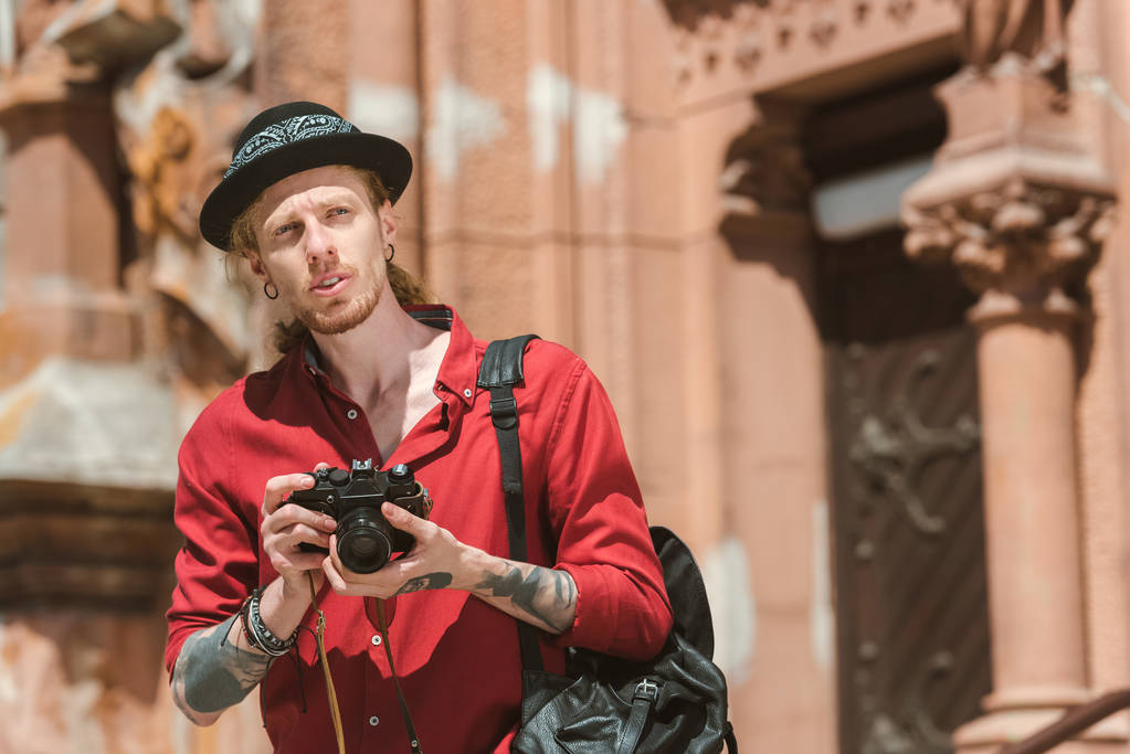 молодий чоловік з рюкзаком фотографується на камеру в місті
  - Фото, зображення