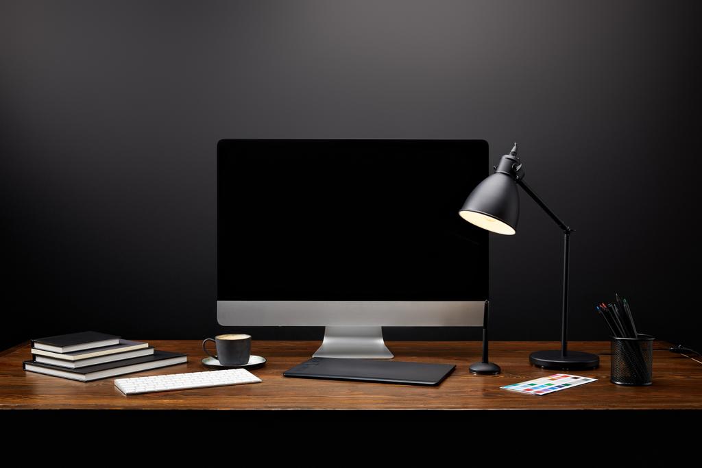 Vista de primer plano del lugar de trabajo del diseñador gráfico con tableta gráfica, pantalla de computadora en blanco, cuadernos y taza de café en la mesa de madera
 - Foto, imagen