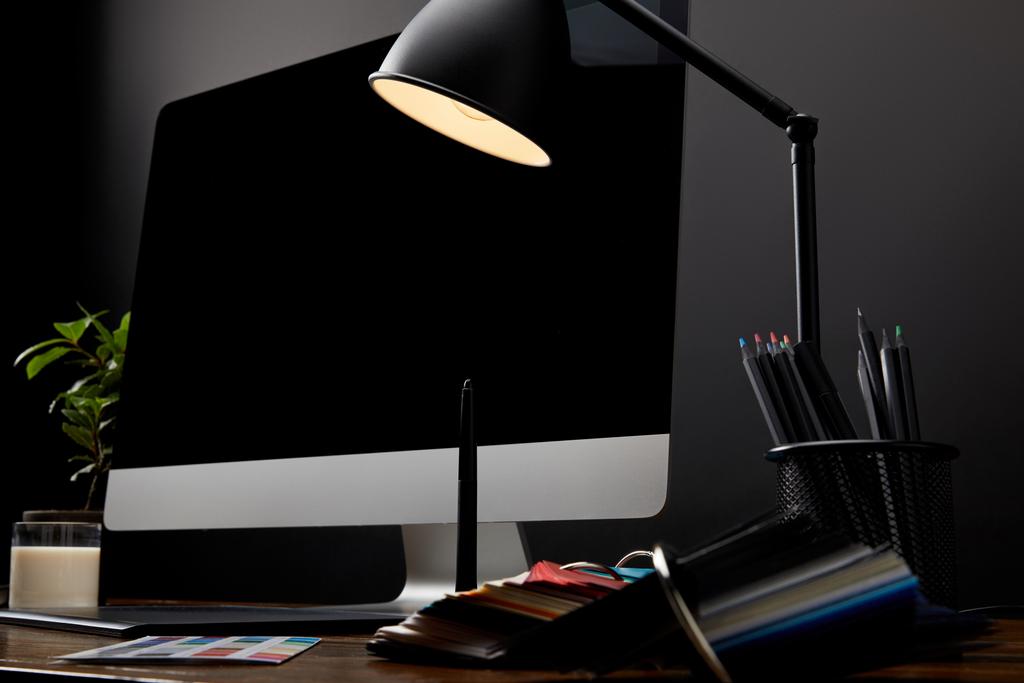 vista de perto do local de trabalho designer gráfico com paletes coloridos, tablet gráfico, tela de computador em branco e lâmpada na superfície de madeira
 - Foto, Imagem
