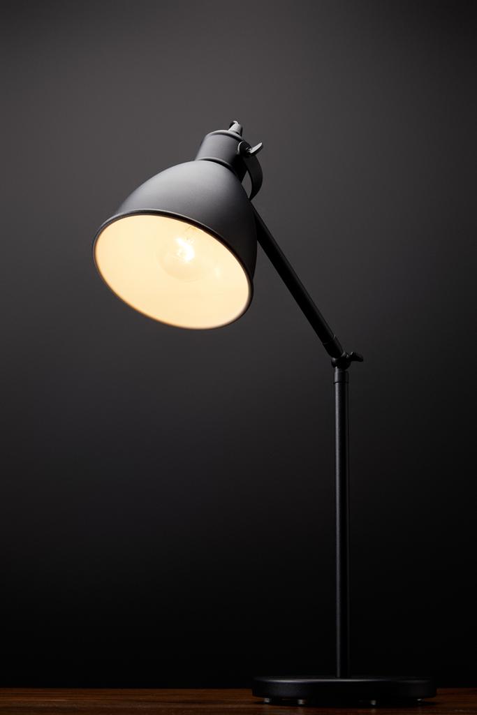 close up vista de lâmpada preta em mesa de madeira no fundo preto
 - Foto, Imagem