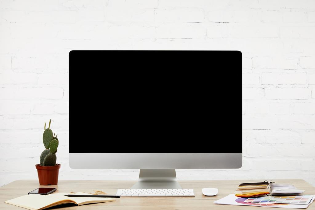 Close-up van ontwerper werkplek met laptop, lege computerscherm, toetsenbord en pallet op houten tafelblad  - Foto, afbeelding