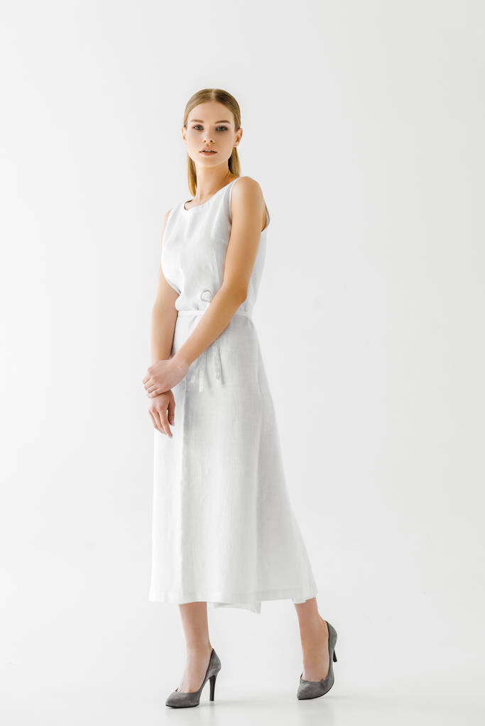 gyönyörű női modell, a vászon fehér ruhában pózol az elszigetelt, a szürke háttér  - Fotó, kép