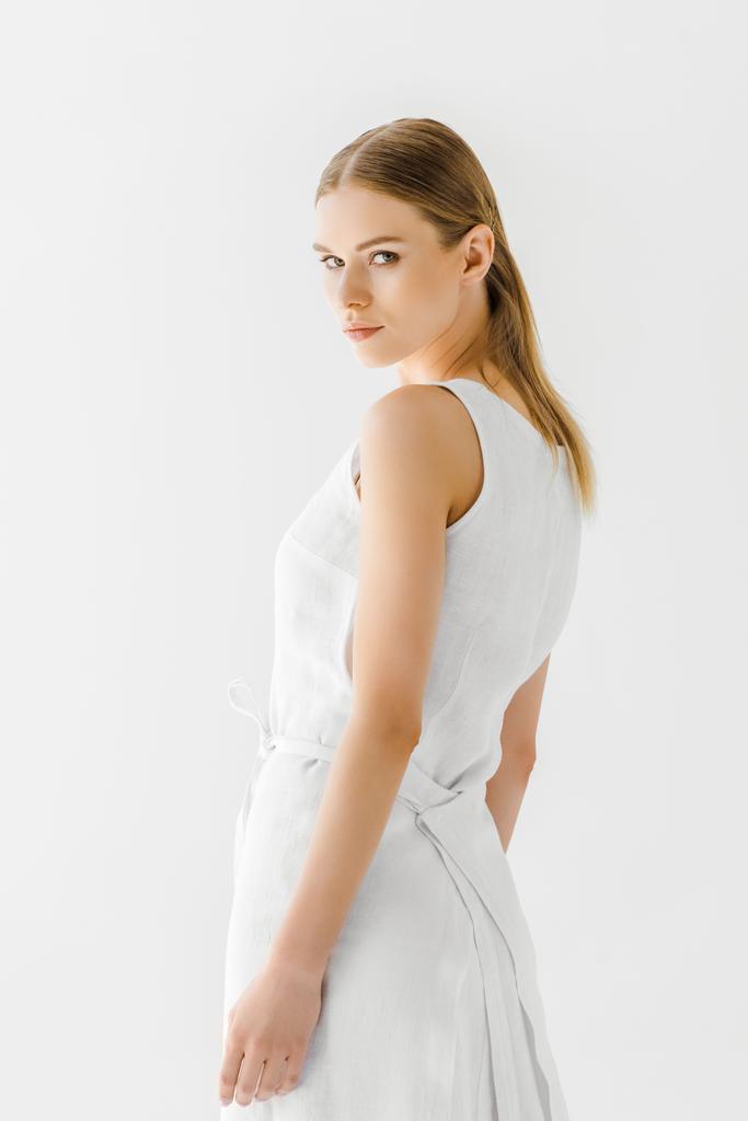 fiatal női modell vászon fehér ruhában pózol az elszigetelt, a szürke háttér  - Fotó, kép