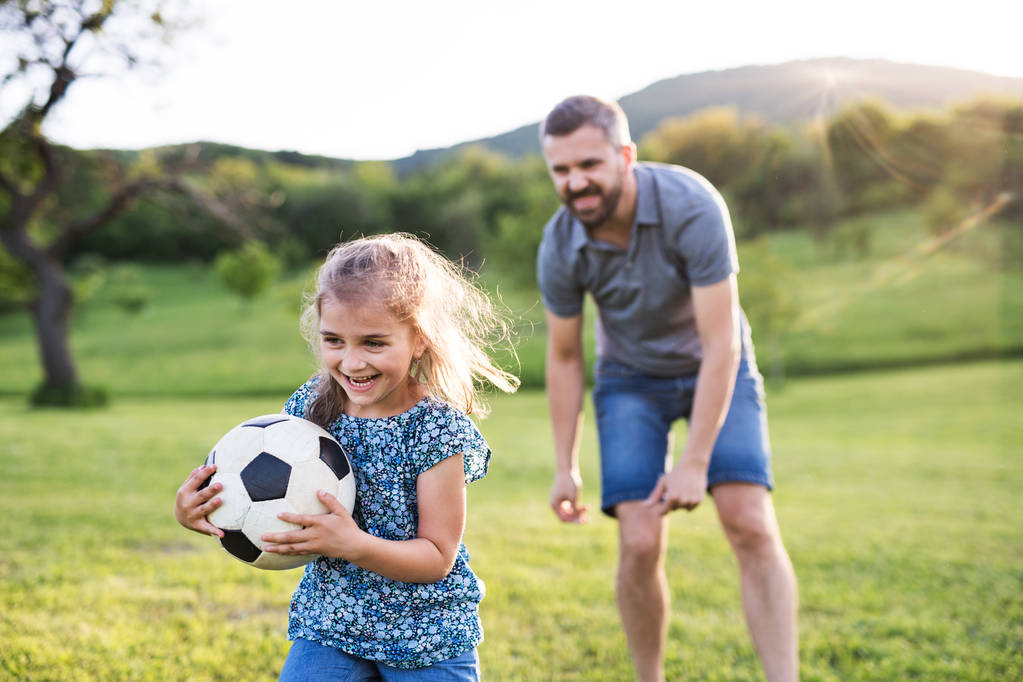 Padre con una piccola figlia che gioca con una palla nella natura primaverile
. - Foto, immagini