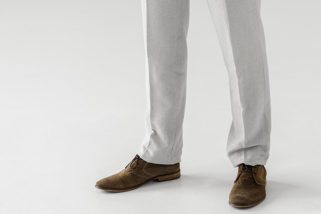 リネンのズボン、灰色の背景に分離されたスエード靴で男性モデルのトリミングされた画像  - 写真・画像