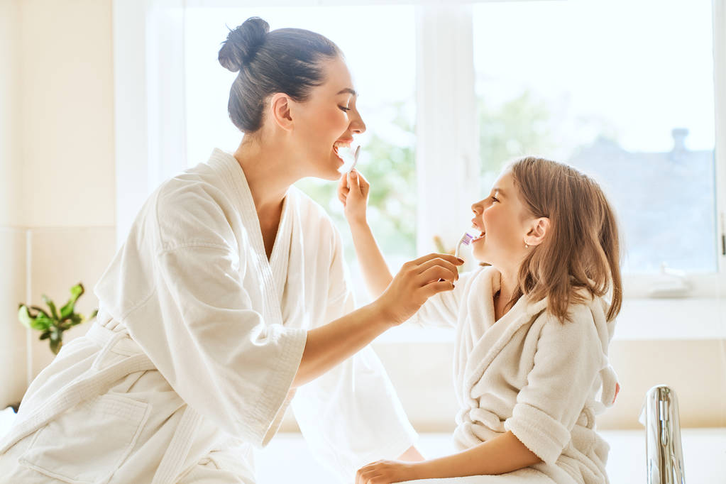 Щаслива сім'я! Мати і дочка дівчинка чистять зубні щітки у ванній
. - Фото, зображення