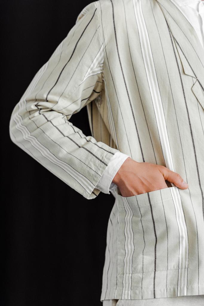 cropped shot of man with hand in pocket of stylish striped jacket isolated on black - Photo, Image
