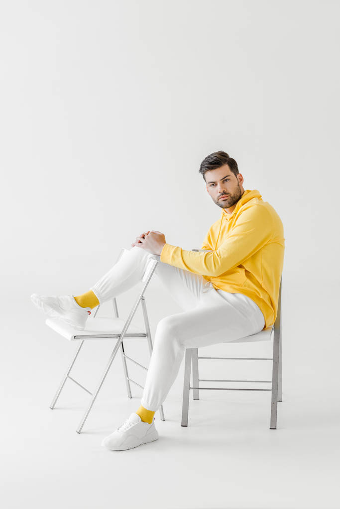 attrayant jeune homme à capuche jaune assis sur des chaises sur blanc
 - Photo, image