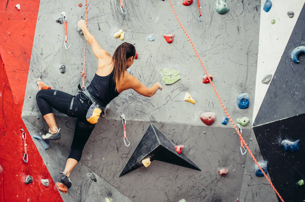 Fit fille étudiante sportive se déplaçant vers le haut au mur d'escalade à la salle de gym - Photo, image