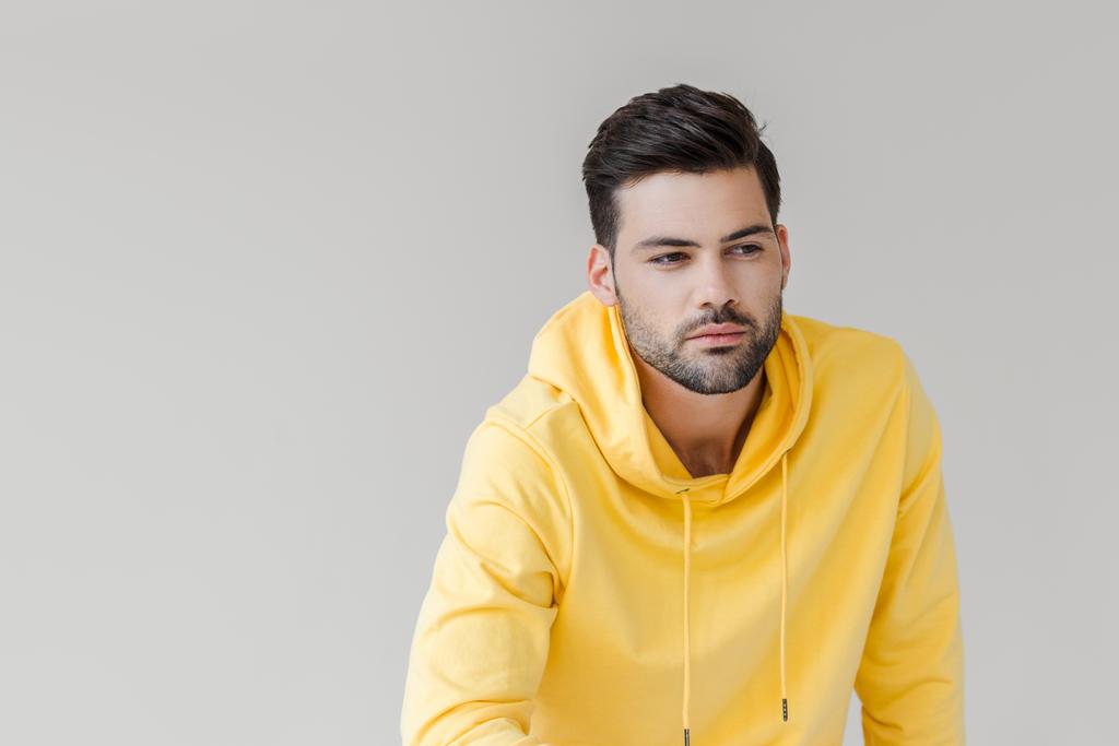 joven guapo con capucha amarilla mirando hacia otro lado aislado en blanco
 - Foto, Imagen