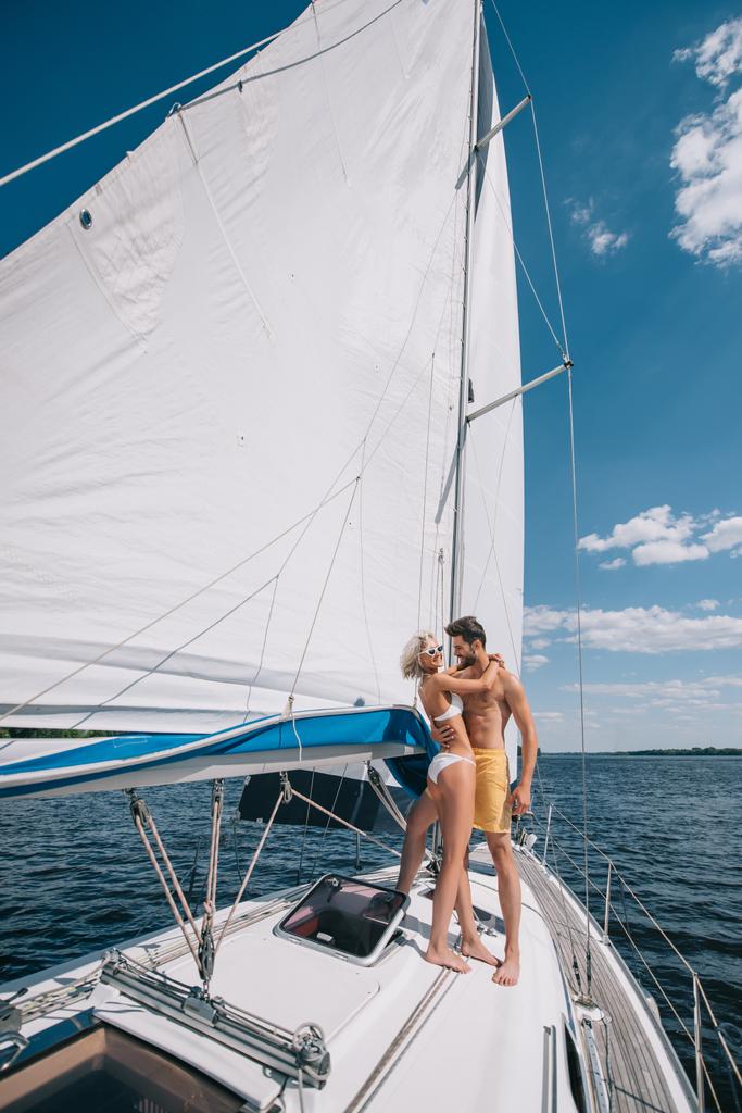 sorridente giovane coppia in costume da bagno che abbraccia su yacht
  - Foto, immagini
