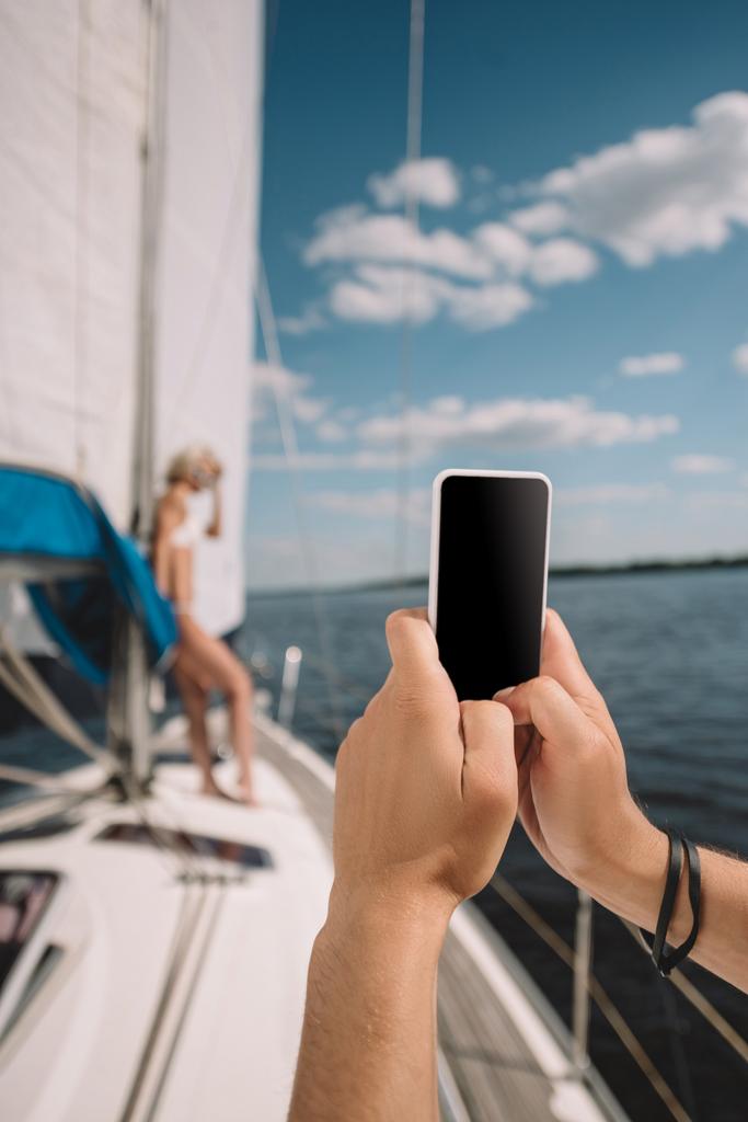 cropped image of man taking picture of girlfriend on smartphone on yacht  - Photo, Image