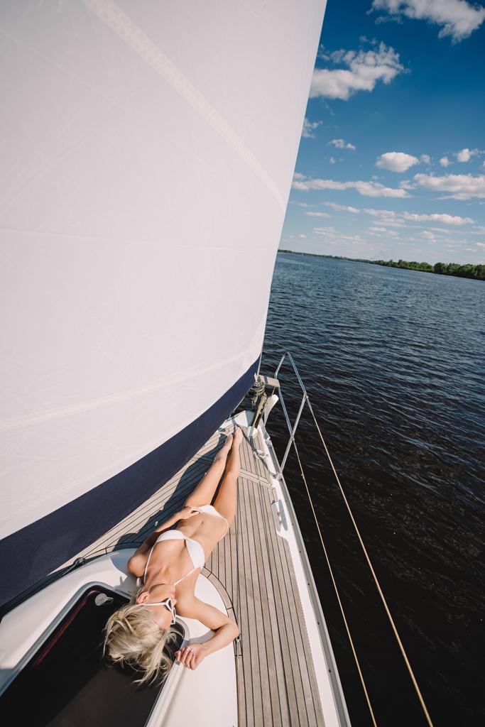 Erhabener Blick auf junge Frau im Bikini beim Entspannen und Sonnenbaden auf Jacht  - Foto, Bild