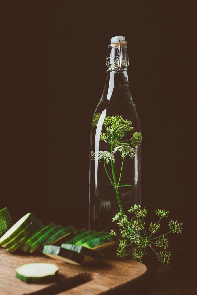 γυάλινο μπουκάλι με νερό και άνηθο, κόψτε τα κολοκυθάκια σε ξύλινη σανίδα - Φωτογραφία, εικόνα