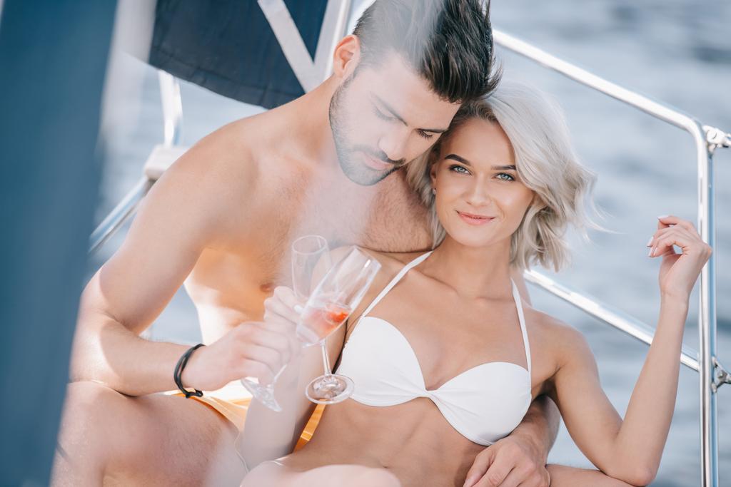 young couple in swimwear clinking by champagne glasses on yacht  - Photo, Image