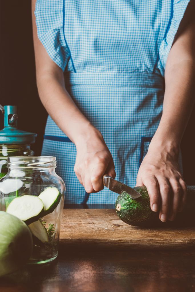 обрезанное изображение женщины, режущей цуккини на деревянной доске на кухне
 - Фото, изображение