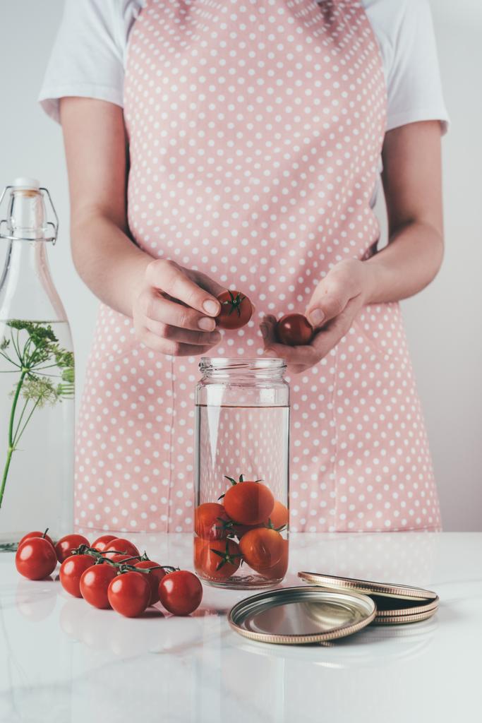image recadrée de la femme mettant des tomates dans un bocal en verre à la cuisine
 - Photo, image