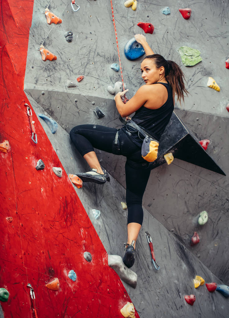 Fitt sportos diák lány mozog felfelé sziklamászás fal az edzőteremben - Fotó, kép