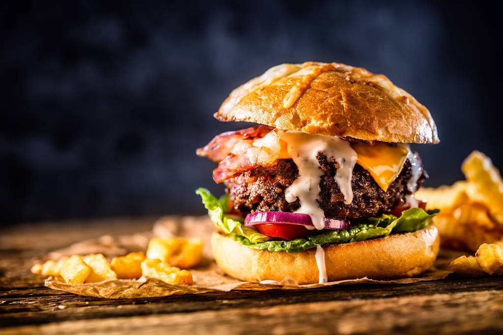 Nahaufnahme hausgemachter Rindfleisch-Burger mit Pommes auf Holztisch. - Foto, Bild