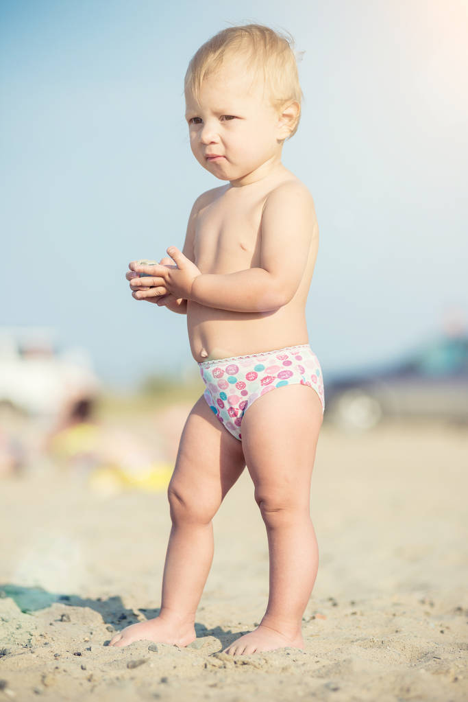 Lindo bebé jugando con juguetes en la playa de arena cerca del mar
. - Foto, imagen