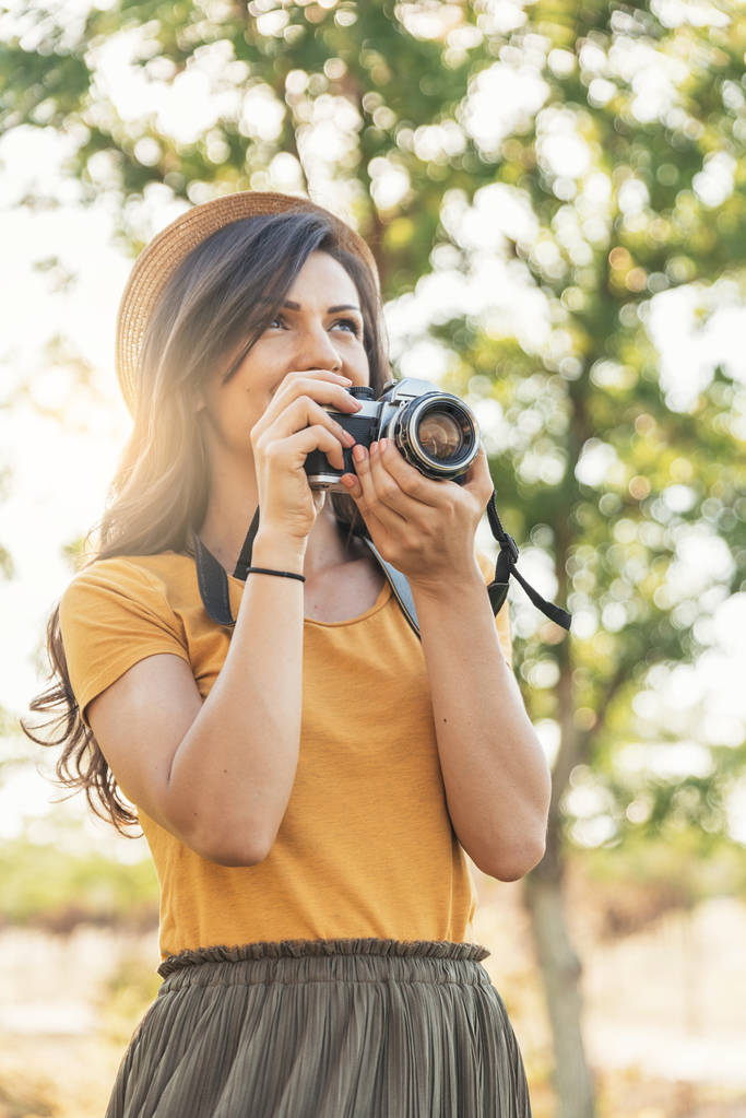 Lächelnde junge Frau mit Kamera für ein Foto im Park. - Foto, Bild