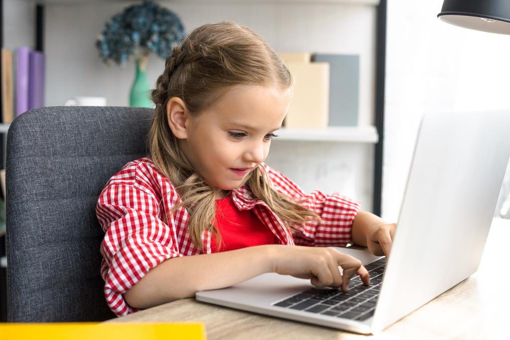 side view of little kid using laptop at table at home - Photo, Image