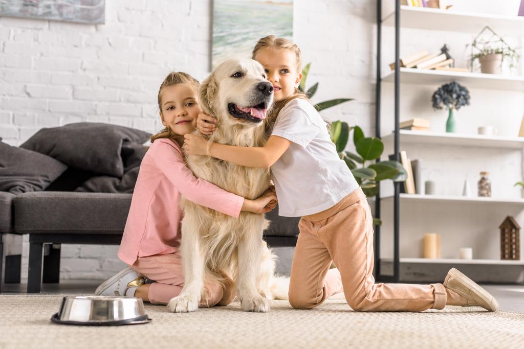 adorable kids hugging golden retriever dog together at home - Photo, Image