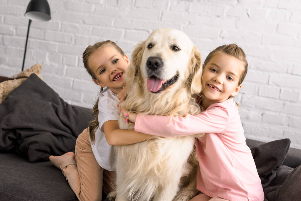 retrato de niños adorables abrazando perro golden retriever en casa
 - Foto, imagen