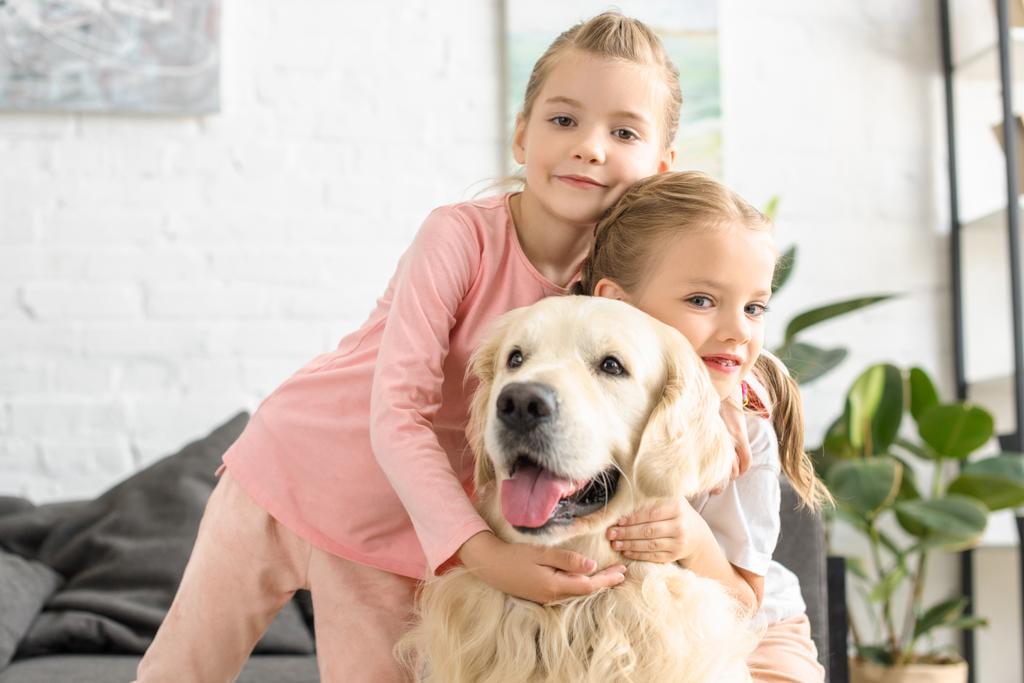 портрет очаровательных детей, обнимающих золотую собаку-ретривера дома
 - Фото, изображение