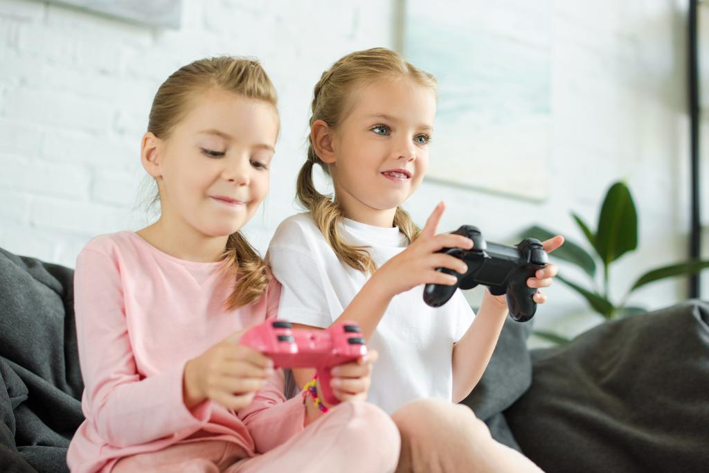portrait de petites sœurs avec des manettes jouant ensemble à un jeu vidéo à la maison
 - Photo, image