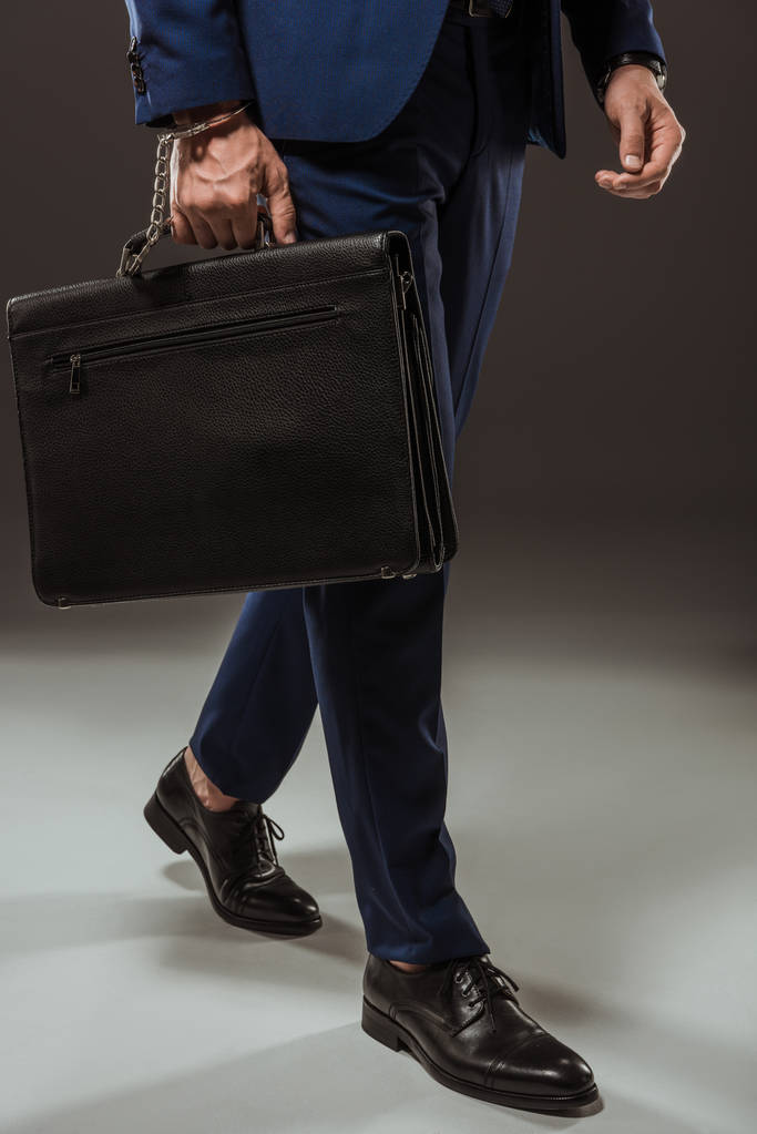 Erschossener Geschäftsmann in Handschellen mit Aktentasche auf schwarz - Foto, Bild