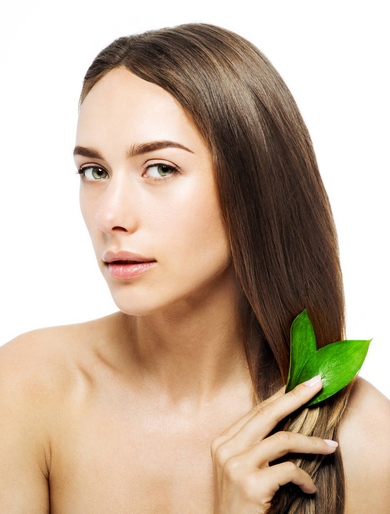 Hermosa mujer con el pelo ideal sosteniendo hojas verdes. Cabello perfecto y piel sana
 - Foto, imagen