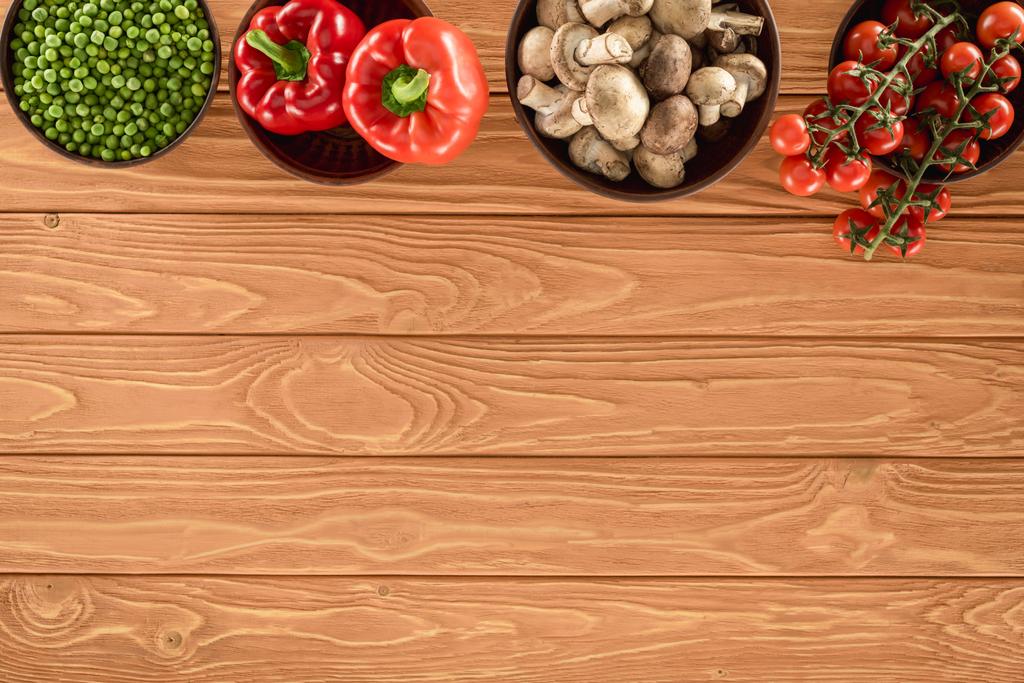 木製のテーブルの上のシャンピニオン キノコとボウルで様々 な野菜トップ ビュー - 写真・画像