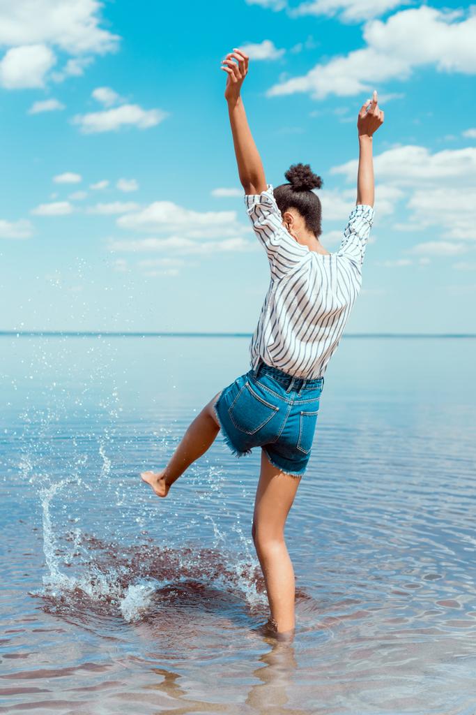 fiatal nő rúgás tengervíz széles karokkal hátsó nézet  - Fotó, kép