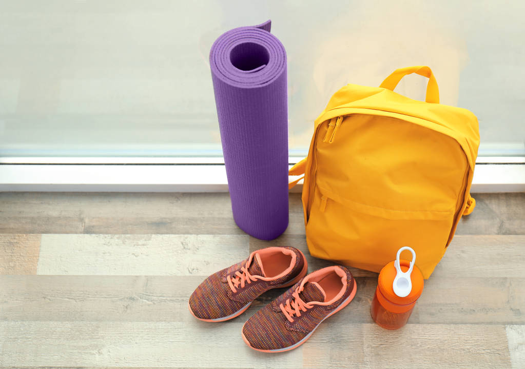 Sport tas en gym apparatuur op houten vloer in de buurt van venster - Foto, afbeelding