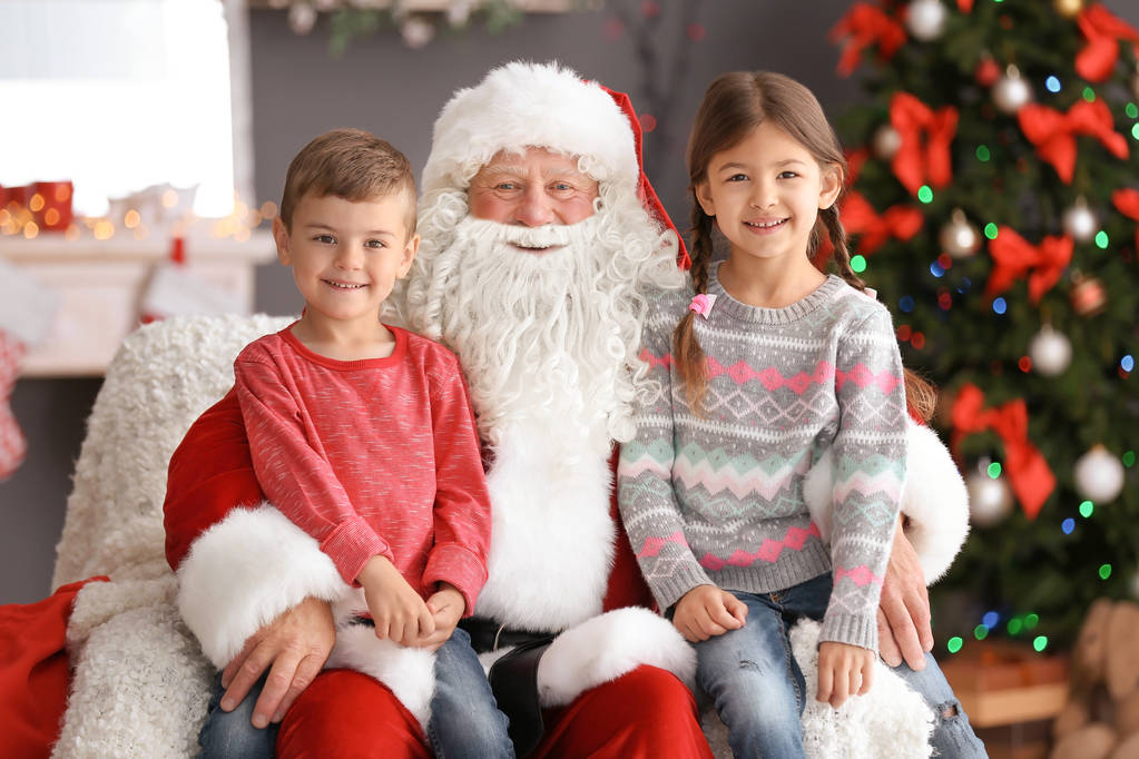 Pienet lapset istuvat aidoilla Joulupukin polvilla sisätiloissa
 - Valokuva, kuva