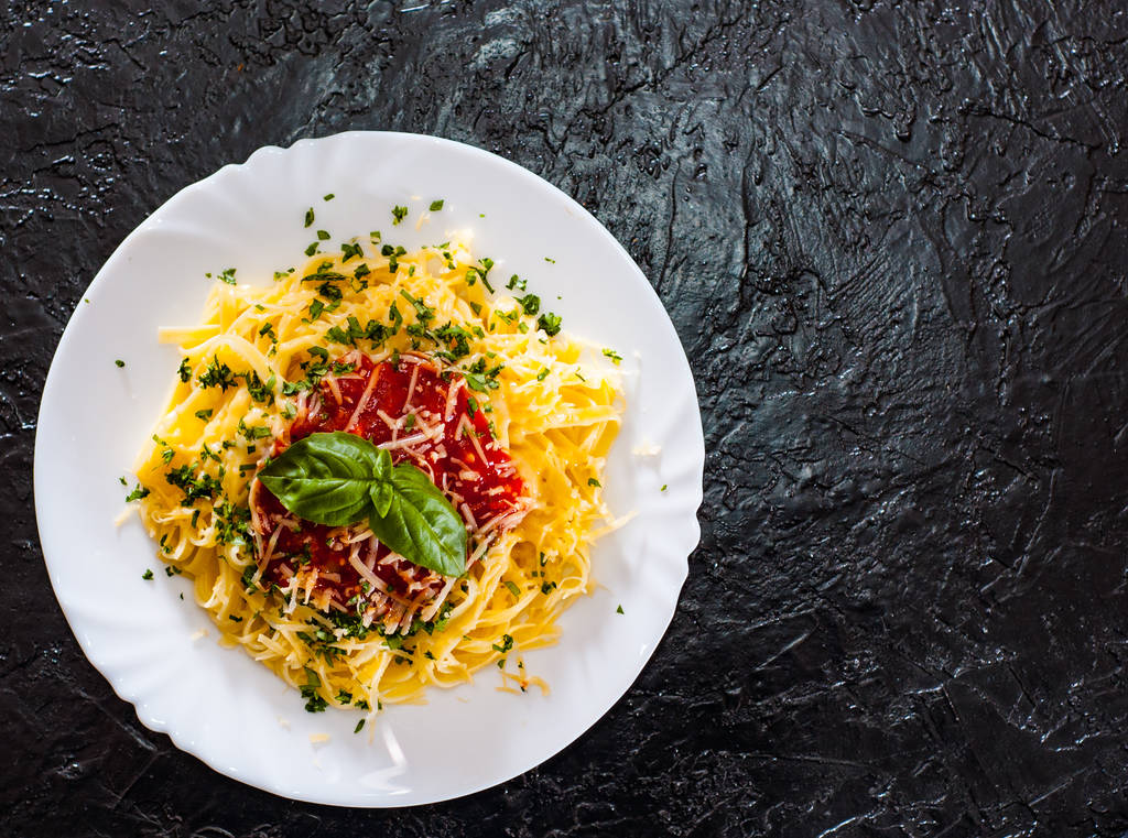 Linguine pasta with fresh tomato sauce, grated cheese and basil in white plate on black background. with copy space. top view - Photo, Image