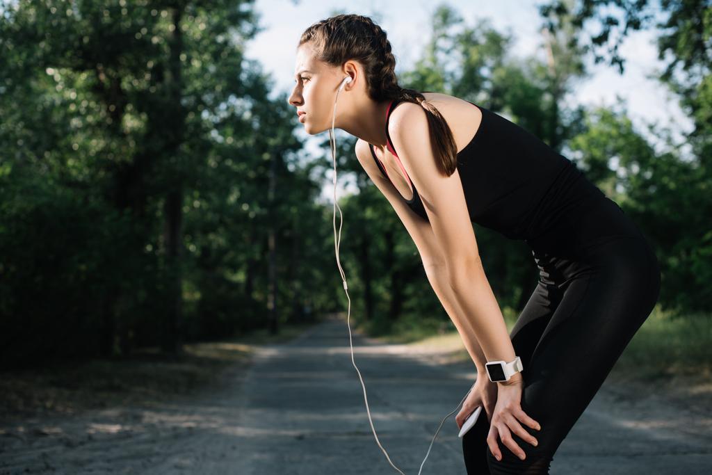 уставшая спортсменка слушает музыку с наушниками и смартфоном
 - Фото, изображение