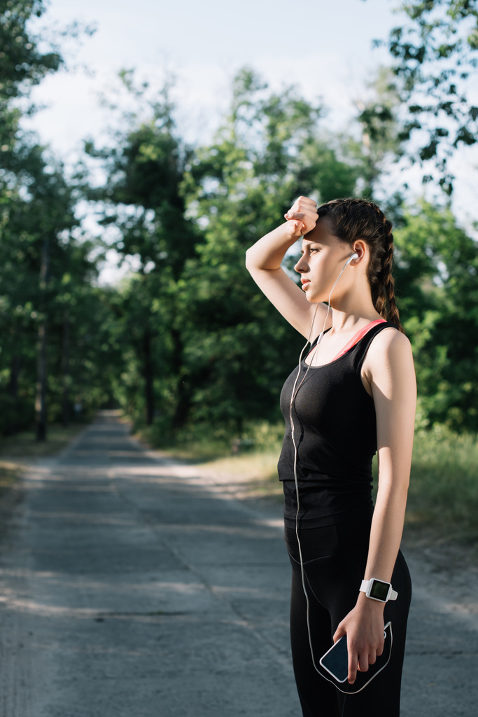 unavená žena sportovní sluchátka, chytré hodinky a smartphone - Fotografie, Obrázek