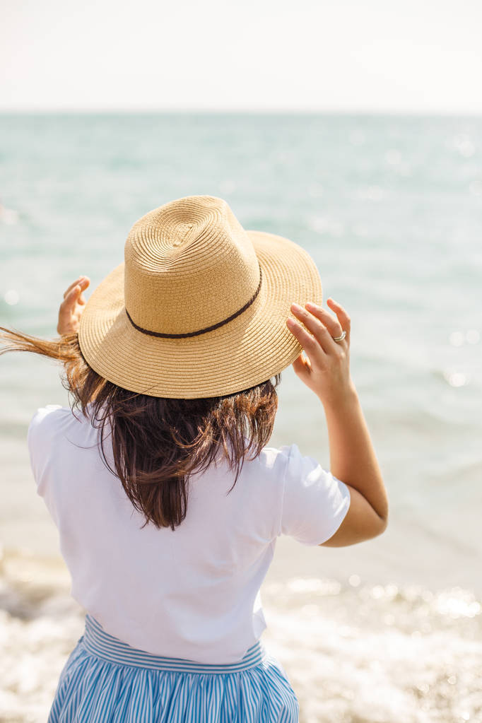 K nepoznání dívka v klobouku kochat pohledem na moře - Fotografie, Obrázek