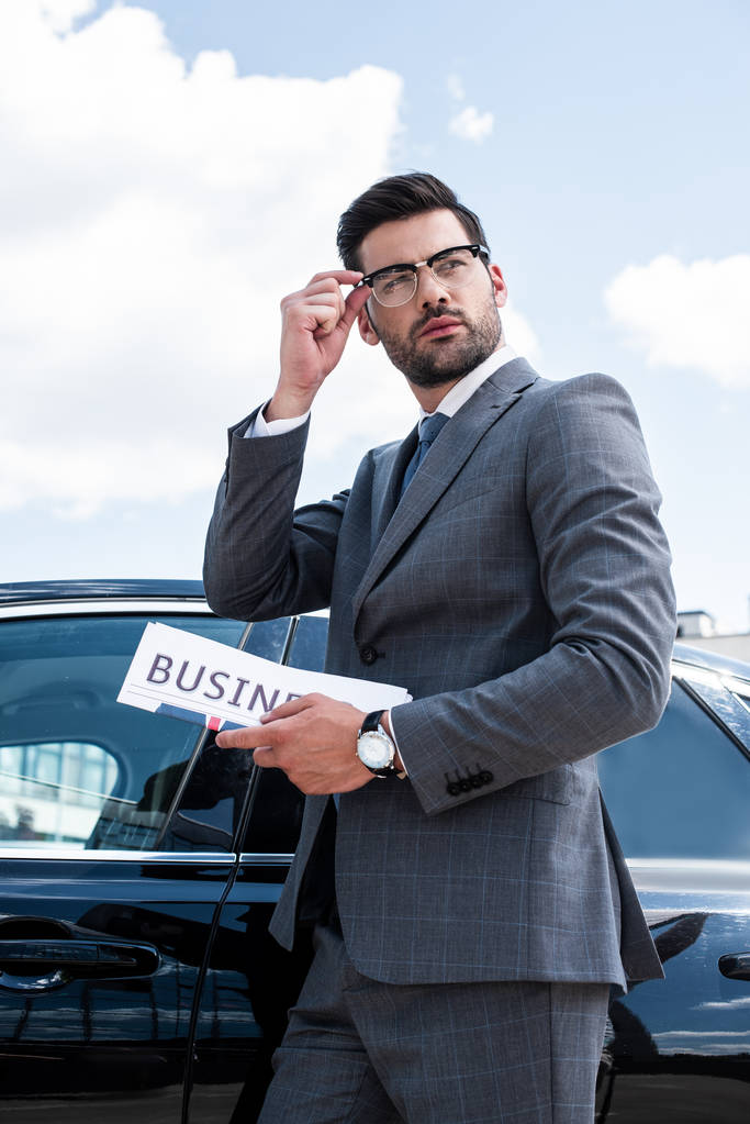 side view of businessman with newspaper standing at car on street - Photo, Image