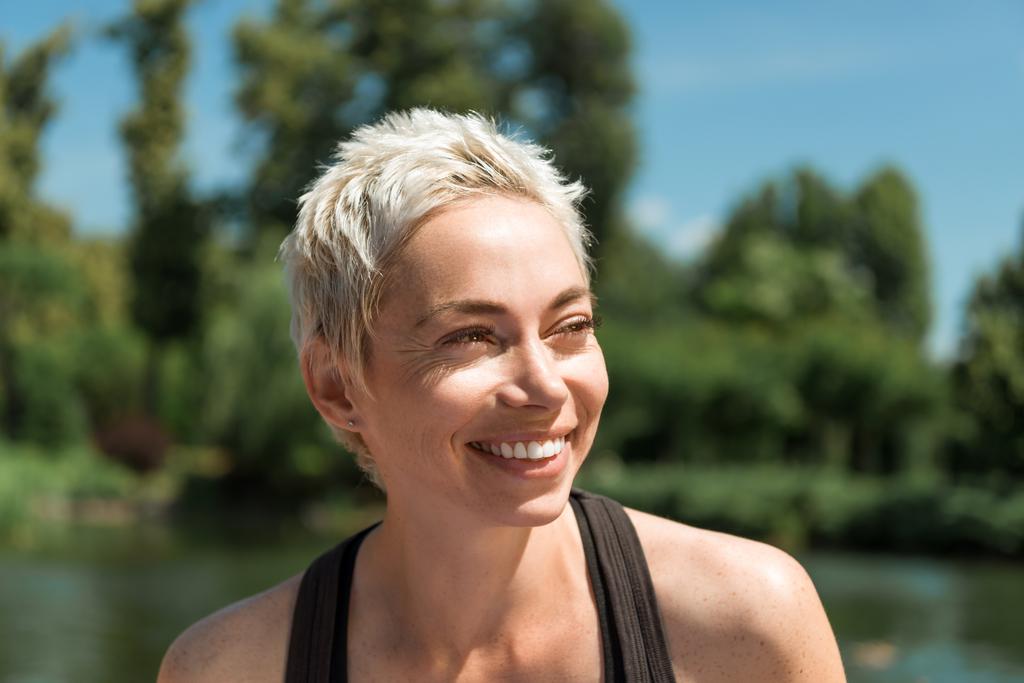 портрет красивой улыбающейся женщины, смотрящей в парк
 - Фото, изображение