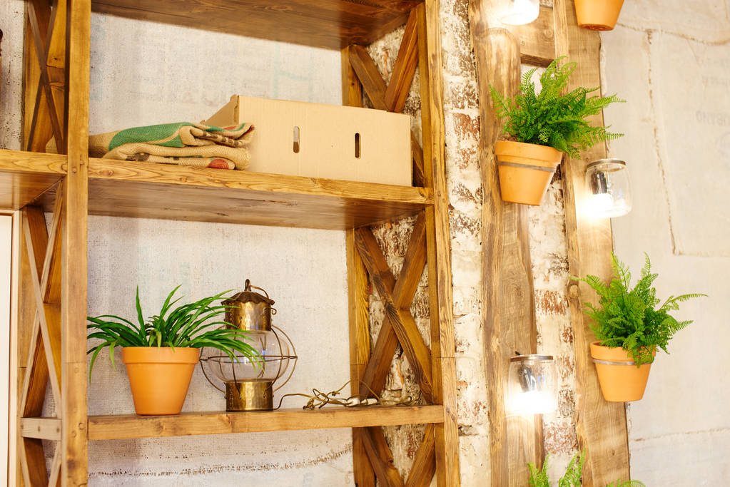 pared con estantes de madera hechos de tablas viejas y plantas en macetas
 - Foto, imagen